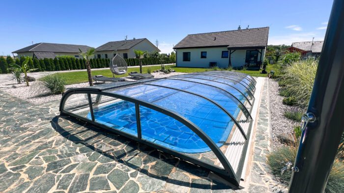 Nadčasové nízké zastřešení s nenápadnými kolejnicemi laminátového bazénu Havai.